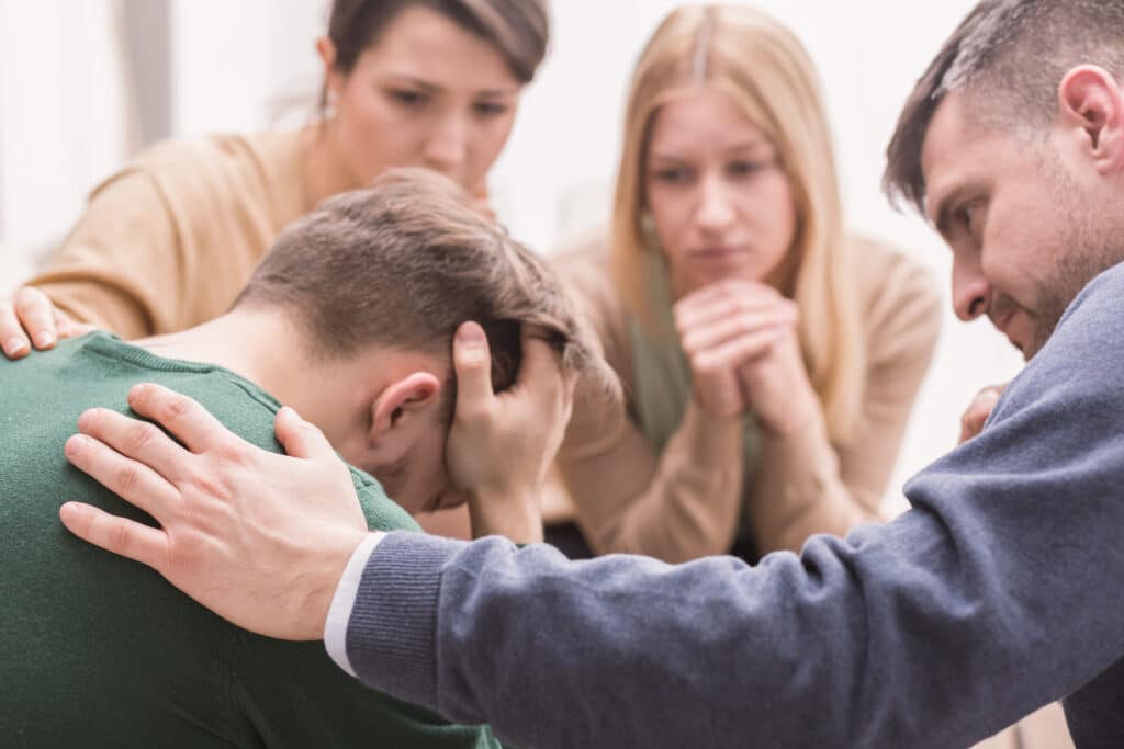 Group of people supporting a young man during group therapy session