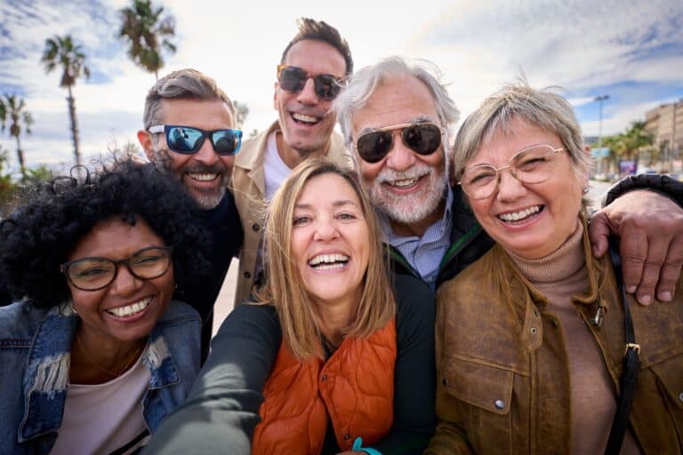 Diverse group of adults smiling together during group therapy or recovery support meeting